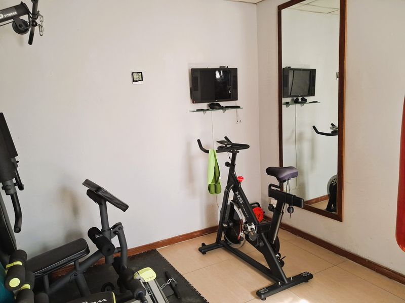 A dedicated home gym space featuring tiled flooring, a large wall-mounted mirror, and neutral wall finishes.