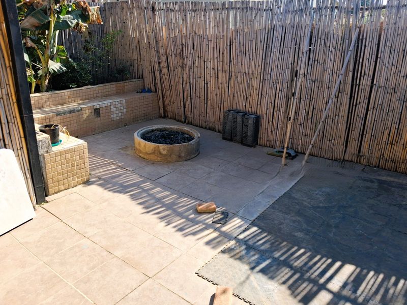 Outdoor patio area featuring a built-in fire pit, tiled seating, and bamboo screen fencing, offering a private space for outdoor entertainment.