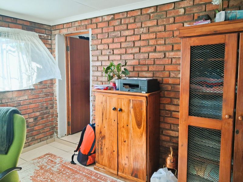 A living area featuring rustic exposed brick walls and tiled flooring, providing a textured and character-filled space.