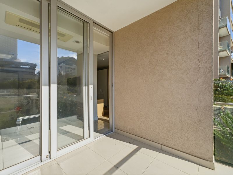 A private balcony featuring tiled flooring, a glass balustrade, and large sliding glass doors providing seamless access to the interior living space.
