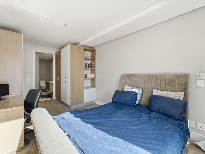 A well-maintained bedroom featuring built-in cupboards, integrated shelving, recessed lighting, and an en-suite bathroom.