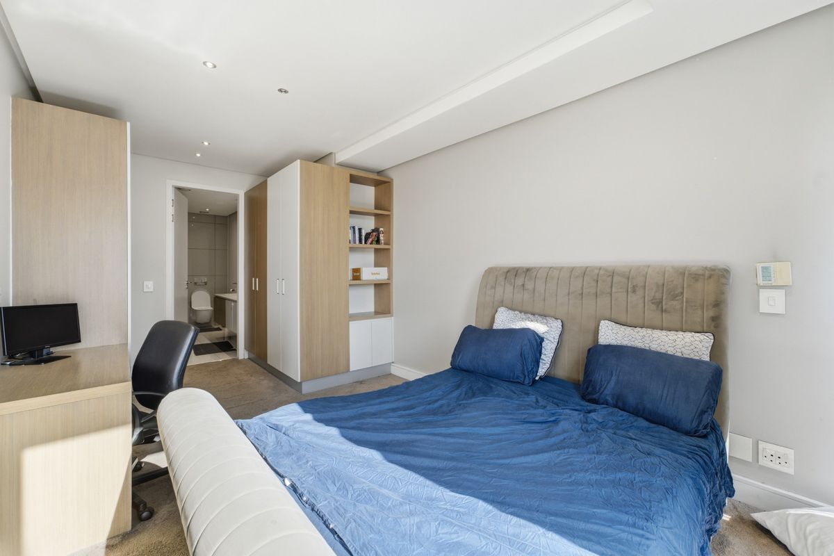 A well-maintained bedroom featuring built-in cupboards, integrated shelving, recessed lighting, and an en-suite bathroom.