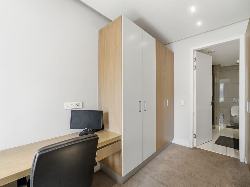 Bedroom featuring a built-in desk and wardrobe, with carpet flooring and direct access to an en-suite bathroom.