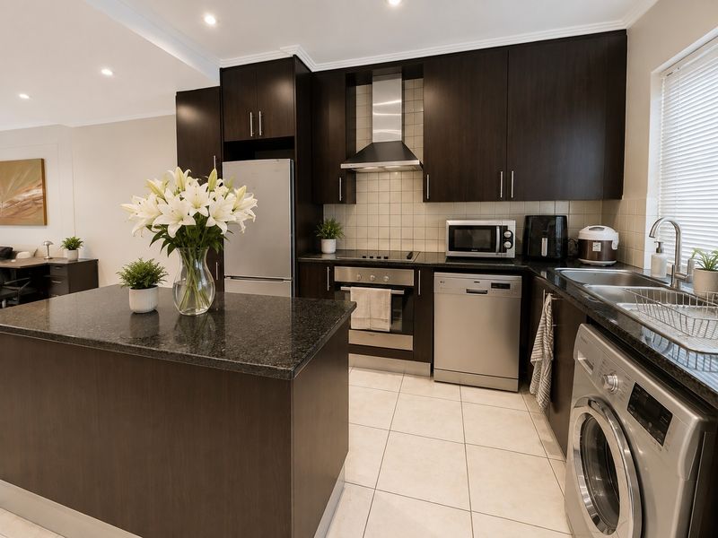 Modern kitchen featuring dark wood cabinetry, granite countertops, stainless steel appliances, and tiled flooring, seamlessly integrated with an open-plan living area.