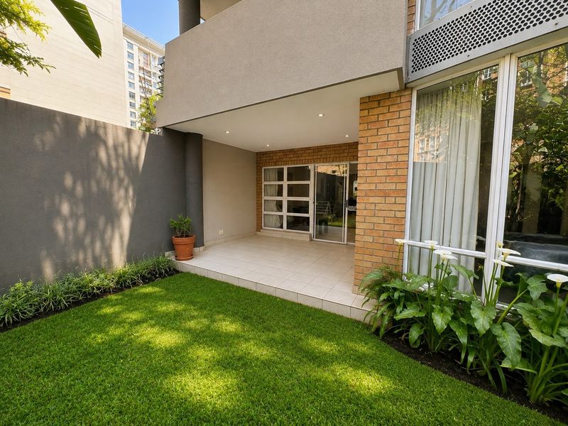A well-maintained ground floor patio featuring tiled flooring, recessed lighting, and direct access to a private garden area through sliding glass doors.
