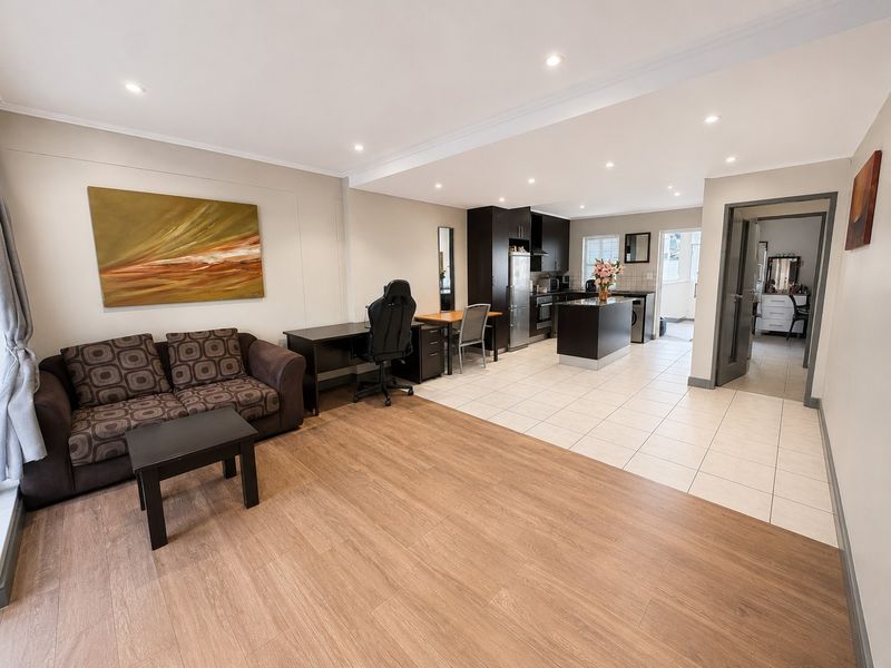 Spacious open-plan living area featuring a modern kitchen with dark cabinetry, an island, and a seamless transition between tiled and laminate flooring.