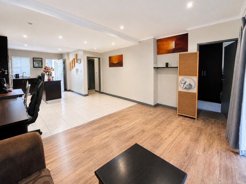 Spacious open-plan living area featuring a combination of tiled and laminate wood flooring, recessed lighting, and a modern kitchen with a central island.