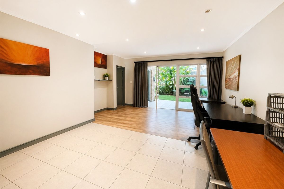 Spacious living area featuring a mix of tiled and wood-look flooring, recessed lighting, and a sliding glass door providing access to the garden.