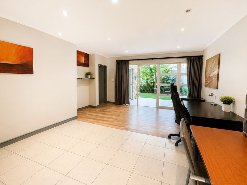 Spacious living area featuring a mix of tiled and wood-look flooring, recessed lighting, and a sliding glass door providing access to the garden.