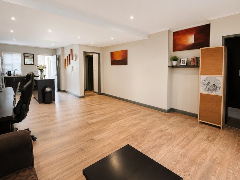 Spacious open-plan living area featuring modern laminate flooring, recessed downlighting, and a functional kitchen island with integrated cabinetry.