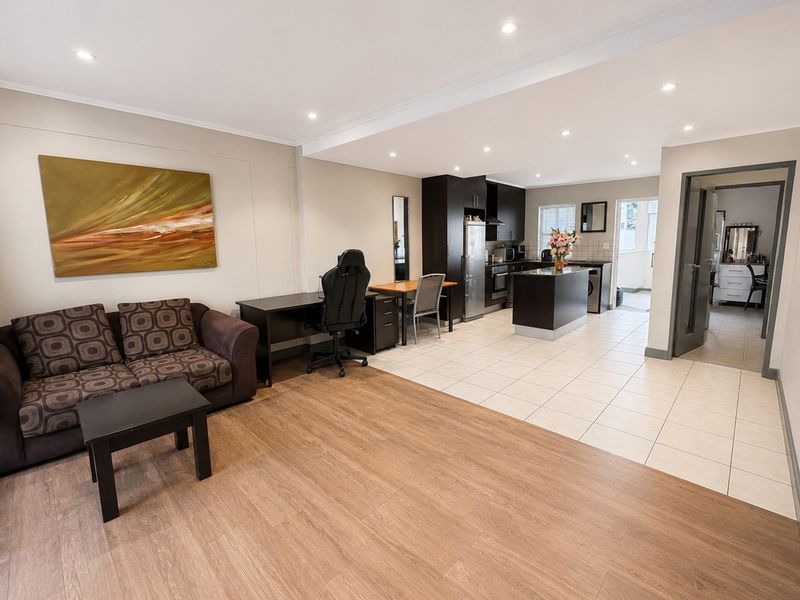 Spacious open-plan living area featuring a modern kitchen with an island, recessed lighting, and a seamless transition between laminate and tiled flooring.