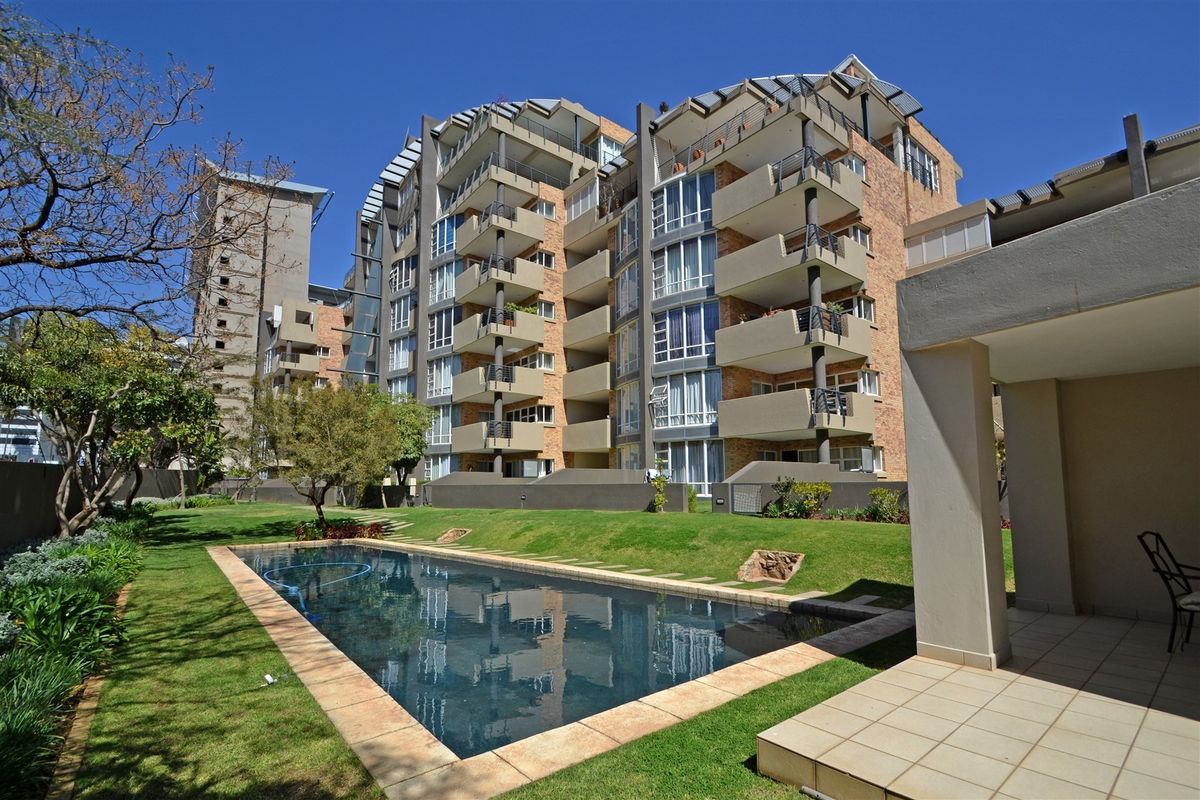 Exterior view of the apartment complex featuring a swimming pool, landscaped garden, and private balconies for the residential units.