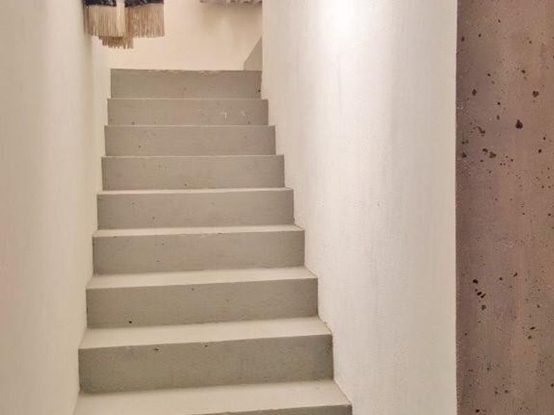 A minimalist staircase featuring concrete steps and a timber handrail, providing a clean and modern architectural transition between levels.