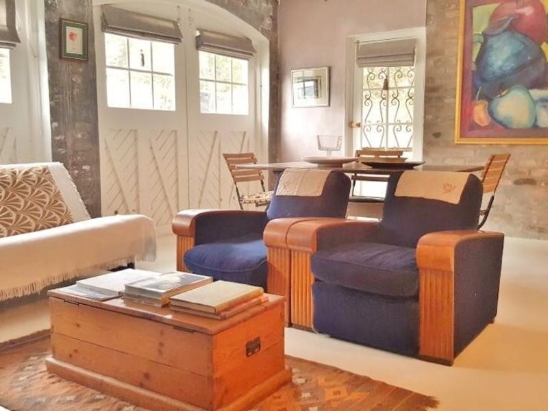 A living room featuring exposed brick walls, arched window detailing, and timber-framed glass doors that provide natural light.