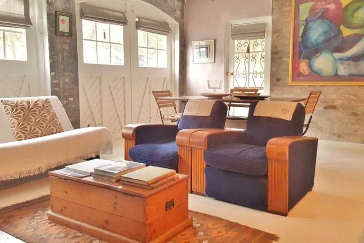 A living room featuring exposed brick walls, arched window detailing, and timber-framed glass doors that provide natural light.