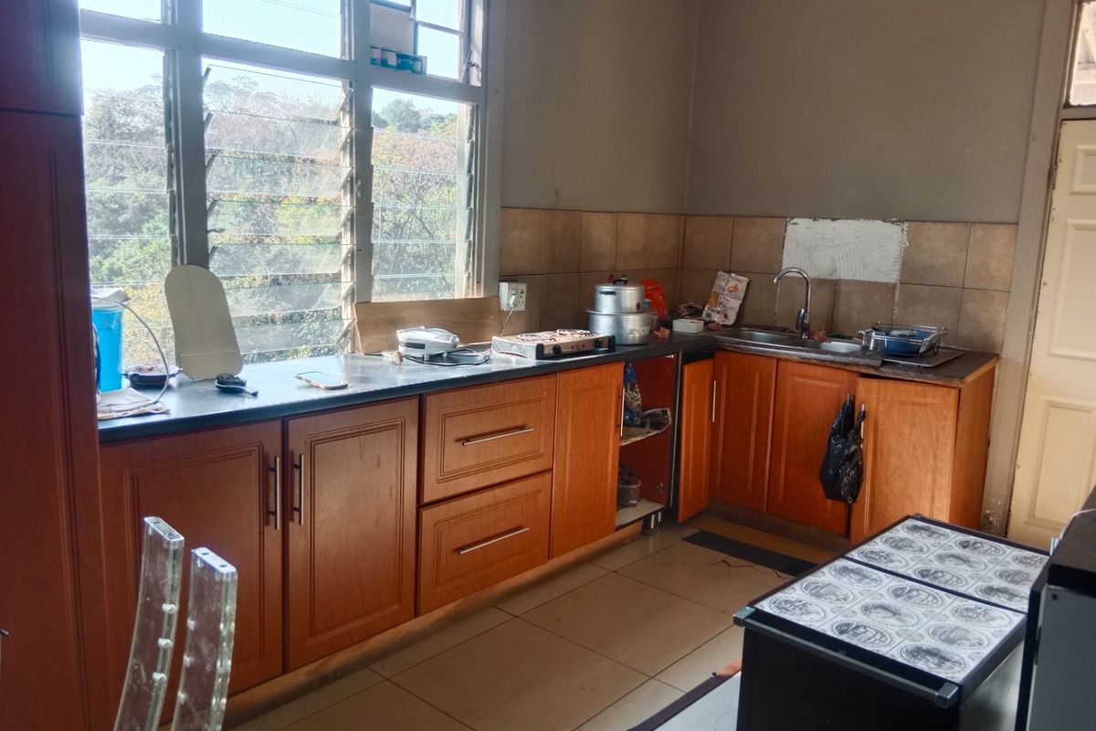A dated kitchen featuring wood-tone cabinetry, tiled backsplash, and a stainless steel sink, offering potential for a modern renovation.