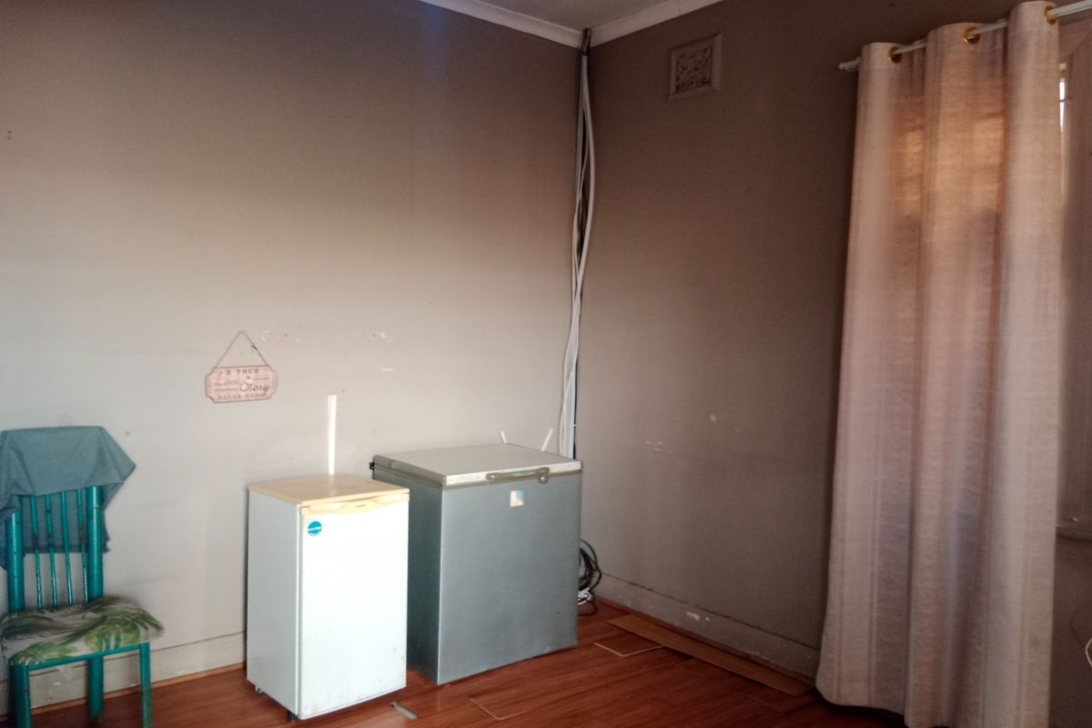 A bedroom featuring laminate flooring and a ceiling fan, currently requiring cosmetic updates and repair to exposed wiring and wall finishes.