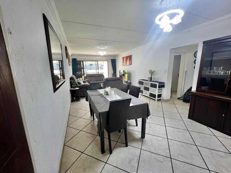 Spacious open-plan living and dining area featuring tiled flooring, modern ceiling lighting, and large sliding doors leading to an outdoor space.