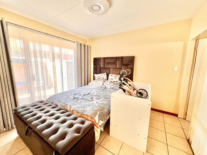 A bedroom featuring tiled flooring and a large sliding glass door providing natural light and access to the exterior.