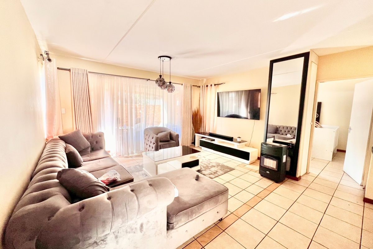 A spacious living room featuring tiled flooring, a gas heater, and a large sliding glass door providing access to the outdoor area.