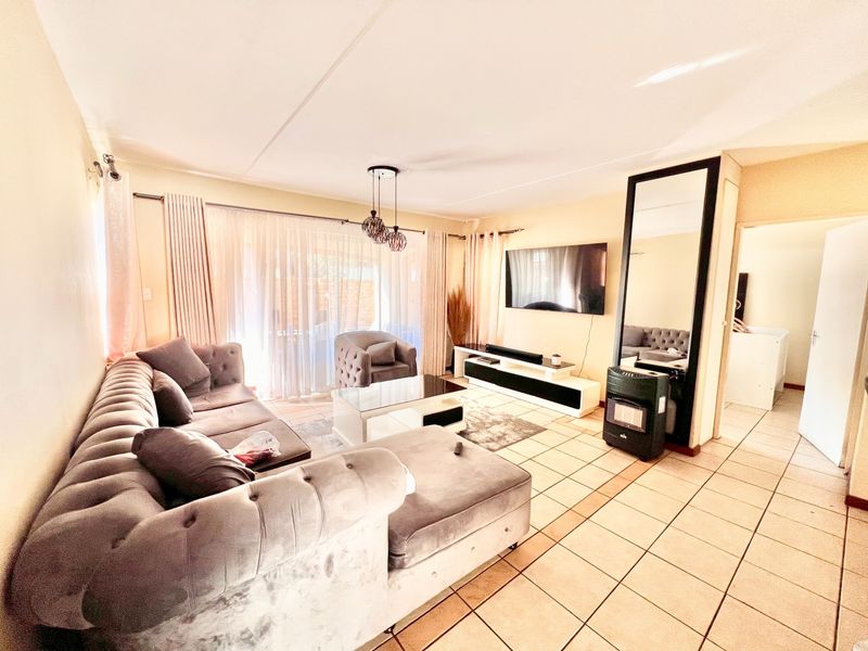 A spacious living room featuring tiled flooring, a gas heater, and a large sliding glass door providing access to the outdoor area.