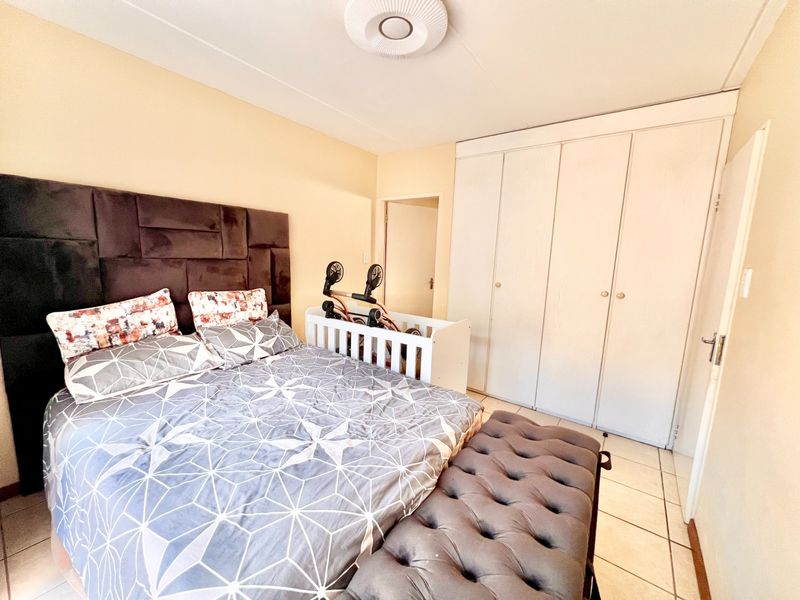 A bedroom featuring built-in cupboards, tiled flooring, and a central ceiling light fixture.