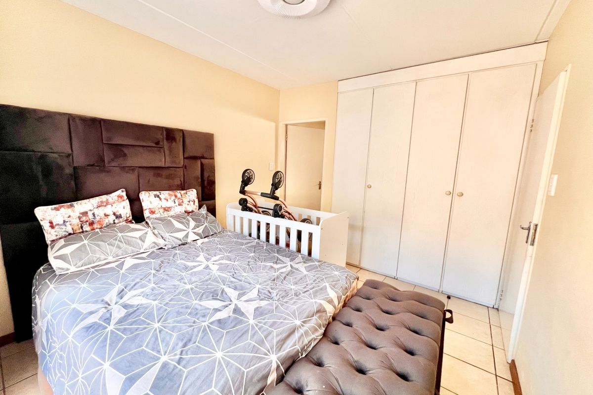 A bedroom featuring built-in cupboards, tiled flooring, and a central ceiling light fixture.