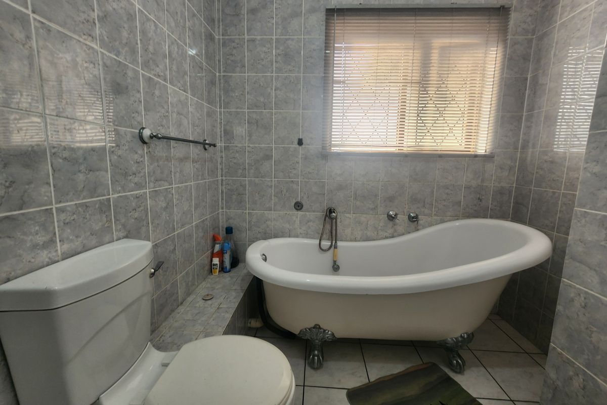A bathroom featuring a classic clawfoot bathtub, ceramic wall and floor tiling, and a standard toilet.