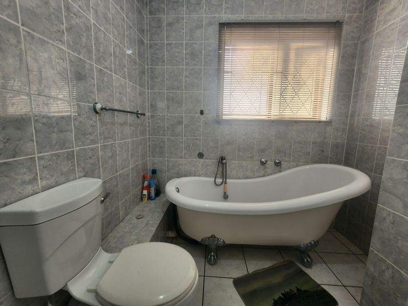 A bathroom featuring a classic clawfoot bathtub, ceramic wall and floor tiling, and a standard toilet.