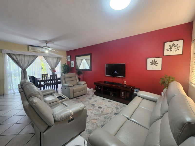 Open-plan living and dining area featuring tiled flooring, a ceiling fan, and a split-system air conditioner with access to an outdoor space.