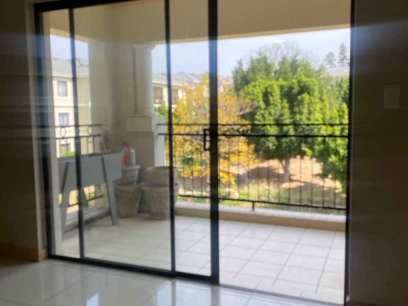 A view from an interior room looking out through a sliding glass door onto a tiled balcony with a wrought iron balustrade.