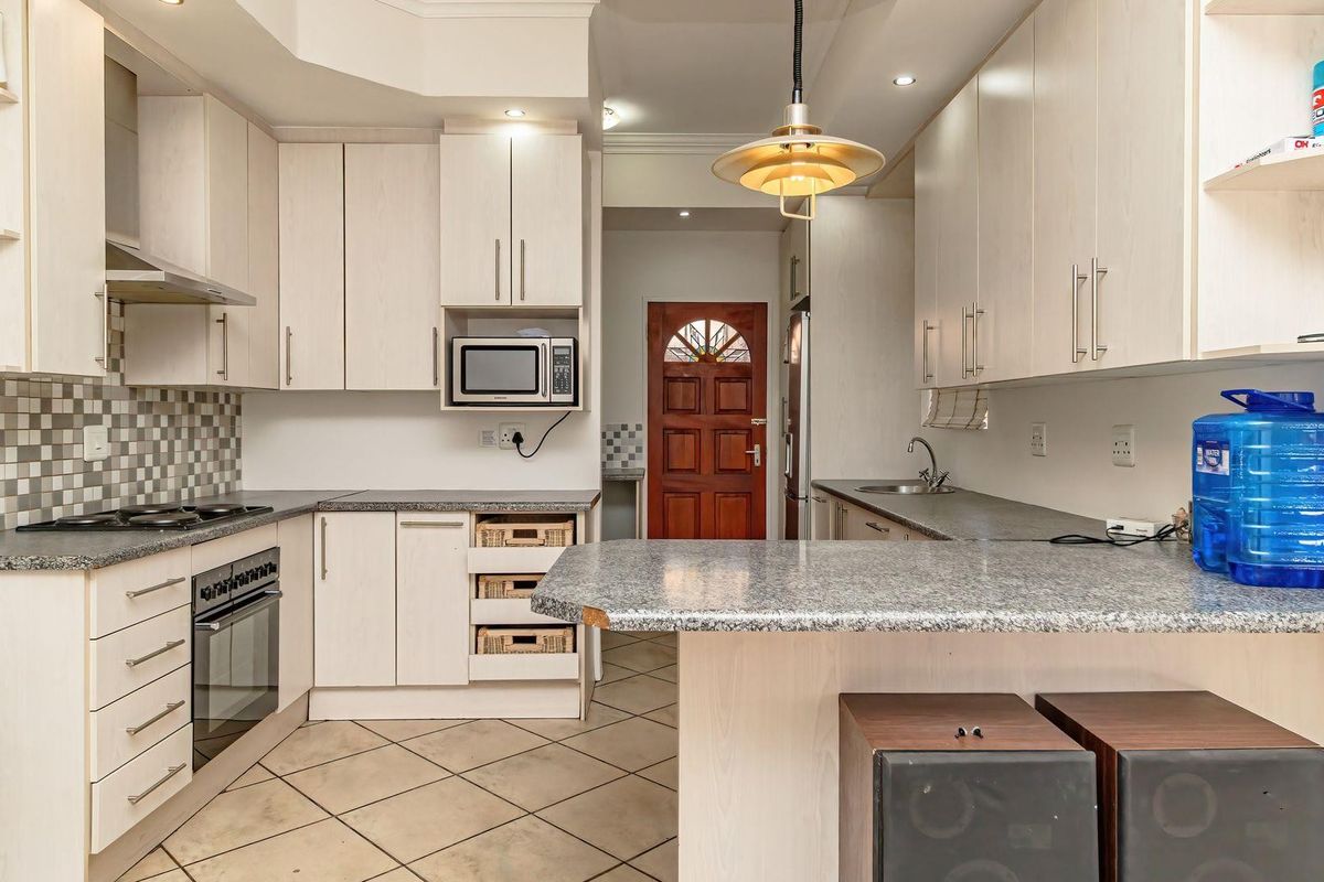 Functional kitchen featuring light wood cabinetry, granite countertops, built-in appliances, and a mosaic tile backsplash with tiled flooring.