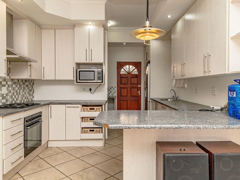 Functional kitchen featuring light wood cabinetry, granite countertops, built-in appliances, and a mosaic tile backsplash with tiled flooring.