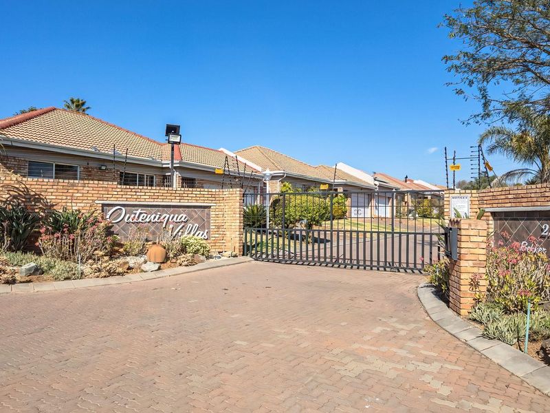 Front entrance view of Outeniqua Villas featuring a paved driveway, secure electric gate, and brick boundary wall with integrated electric fencing.
