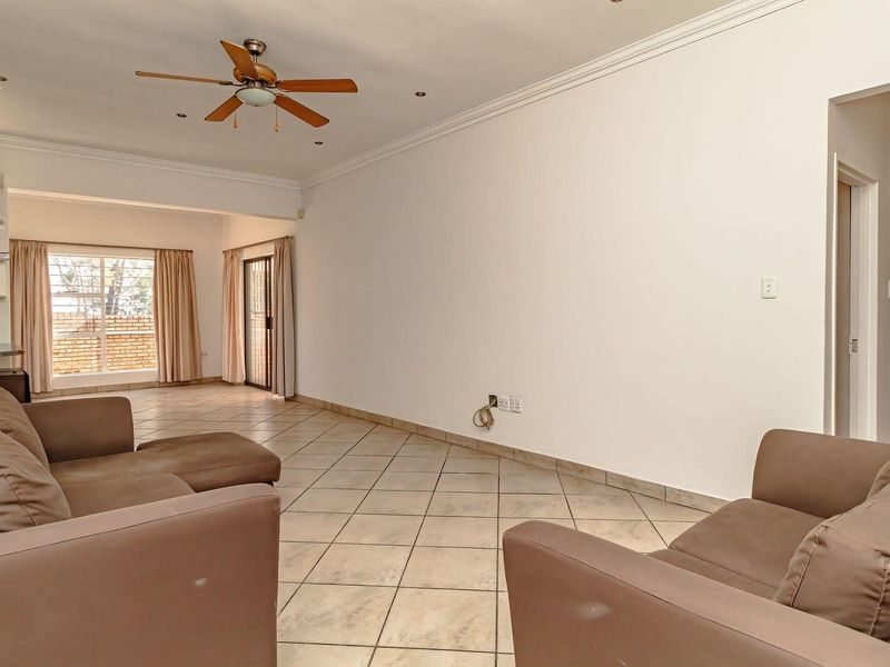 Spacious open-plan living area featuring tiled flooring, crown molding, recessed lighting, a ceiling fan, and direct access to the outdoor area via sliding doors.