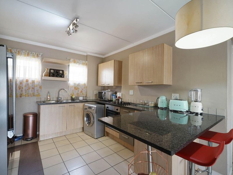 Functional kitchen featuring light wood cabinetry, granite countertops, a breakfast bar, and tiled flooring, providing a practical workspace for daily cooking.
