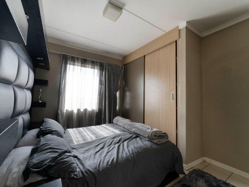 A bedroom featuring a built-in wardrobe with sliding doors and a window with curtains.