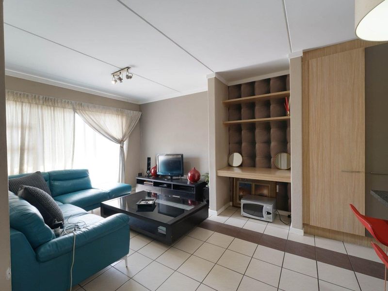 Open plan living area featuring tiled flooring, built-in shelving, and integrated cabinetry, providing a functional and versatile space for relaxation and storage.
