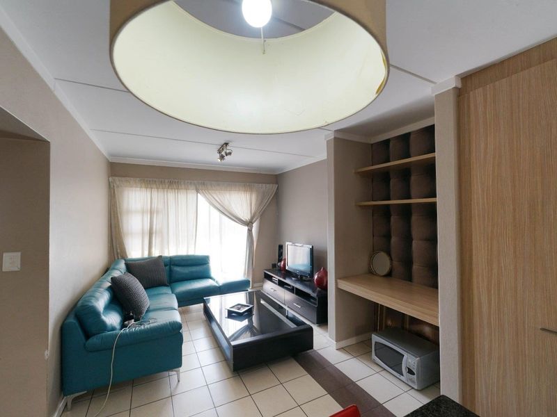 A living room featuring tiled flooring, built-in shelving, and a dedicated desk area, providing a functional and versatile space.