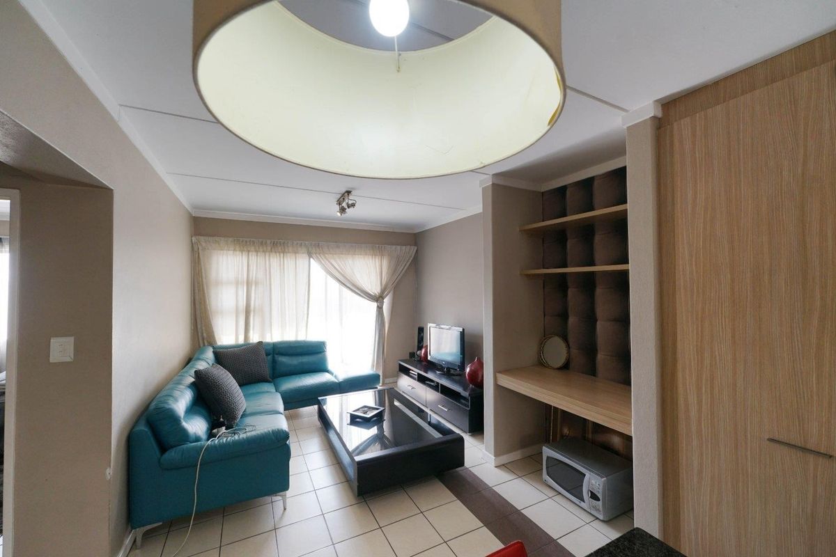 A living room featuring tiled flooring, built-in shelving, and a dedicated desk area, providing a functional and versatile space.