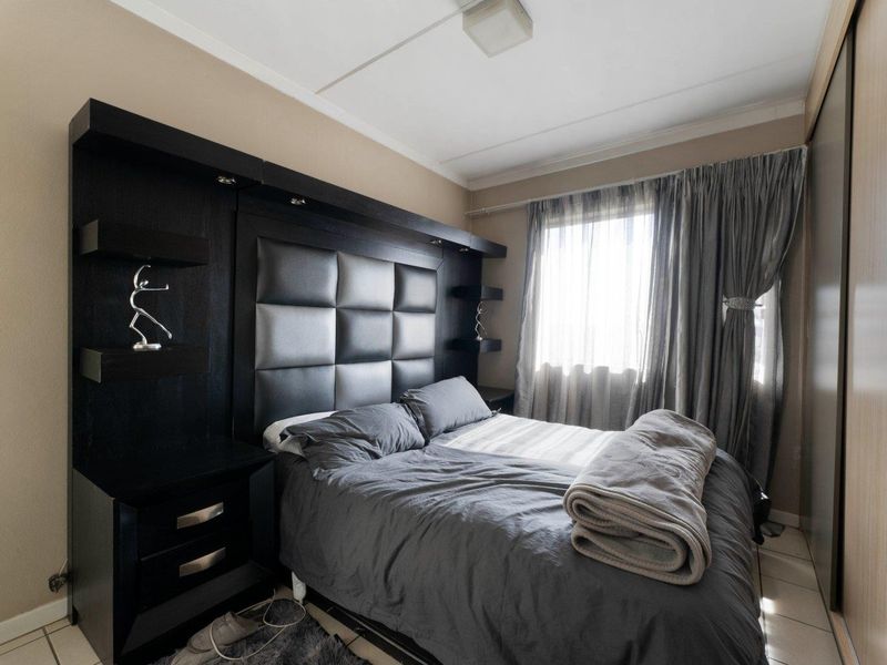 A well-maintained bedroom featuring a modern built-in headboard with integrated bedside tables and a large sliding door wardrobe.