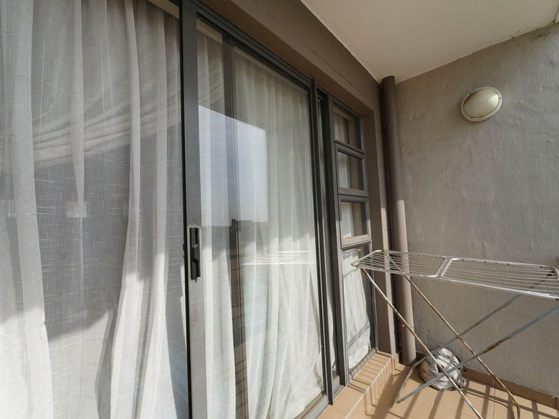 A functional balcony space featuring tiled flooring, a metal safety railing, and large sliding glass doors providing access to the interior.