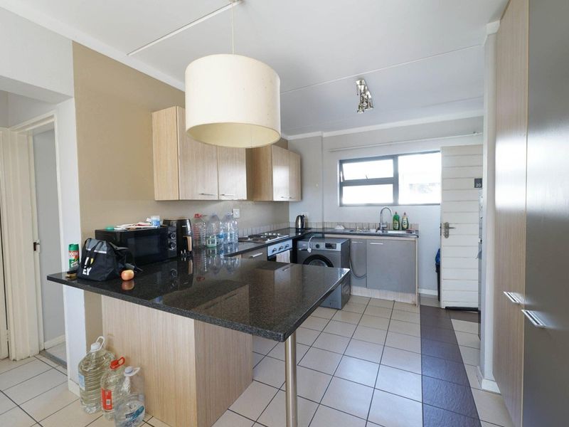 Functional kitchen featuring granite countertops, built-in cabinetry, a breakfast bar, and tiled flooring, providing a practical layout for daily cooking and dining.