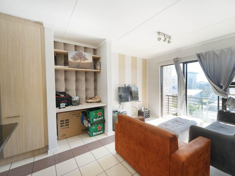 A living room featuring tiled flooring, built-in shelving, and a sliding glass door providing access to an outdoor balcony area.