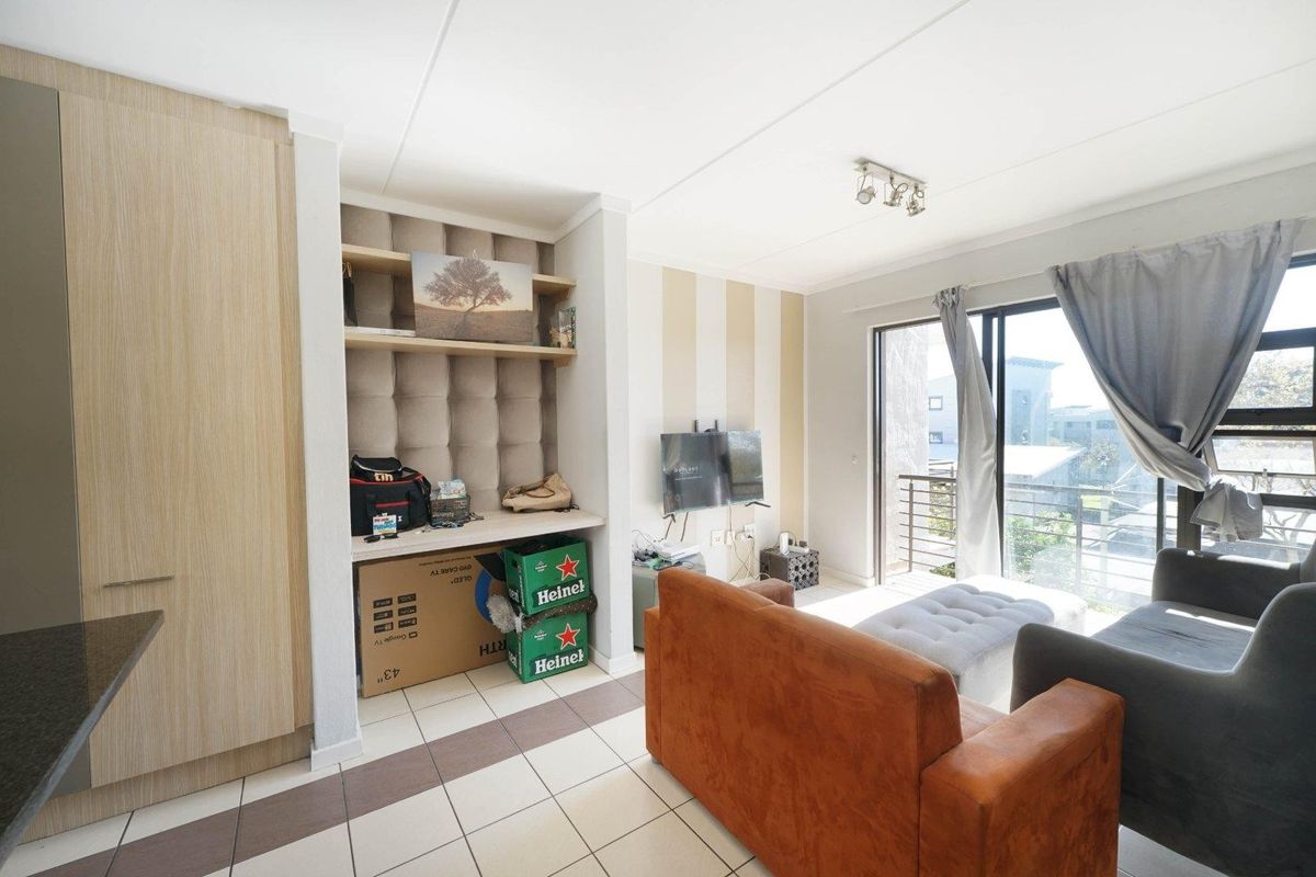 A living room featuring tiled flooring, built-in shelving, and a sliding glass door providing access to an outdoor balcony area.