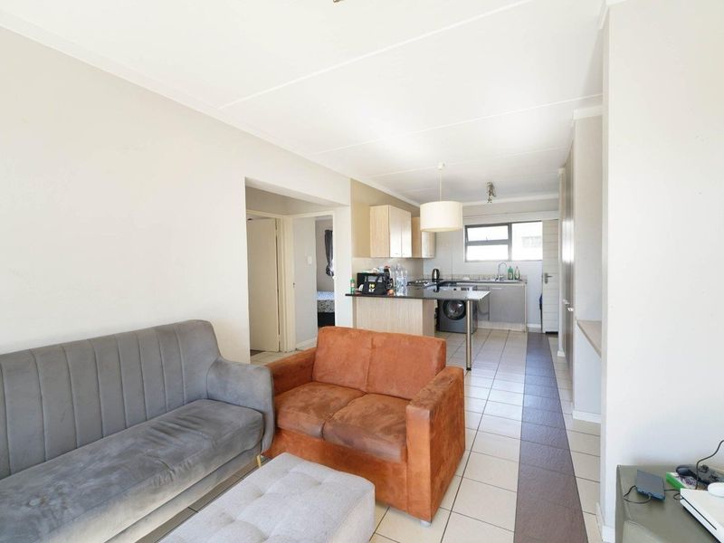 Open-plan living area featuring a functional kitchen with cabinetry, breakfast counter, and tiled flooring, seamlessly connected to the lounge space.