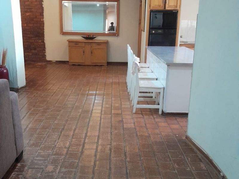 Open plan living and kitchen area featuring a brick accent wall, tiled flooring, and a central kitchen island with built-in oven.