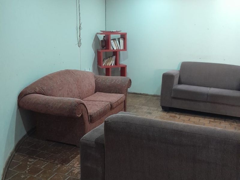 A living room featuring tiled flooring, recessed downlighting, and coving, currently requiring cosmetic updates to the wall finishes and flooring.