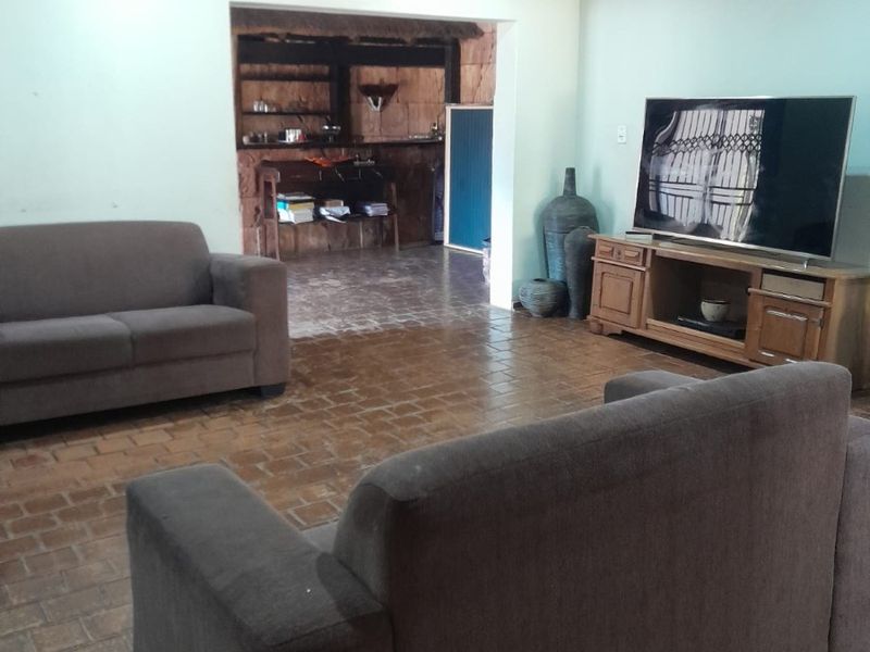Spacious living room featuring terracotta tile flooring, recessed downlighting, and a coved ceiling, with an open transition to an adjacent secondary area.