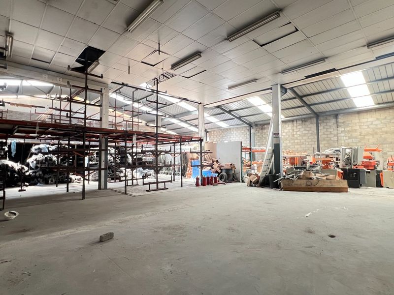 Spacious industrial warehouse featuring high ceilings with skylights, concrete flooring, and a built-in steel mezzanine structure for storage or operational use.
